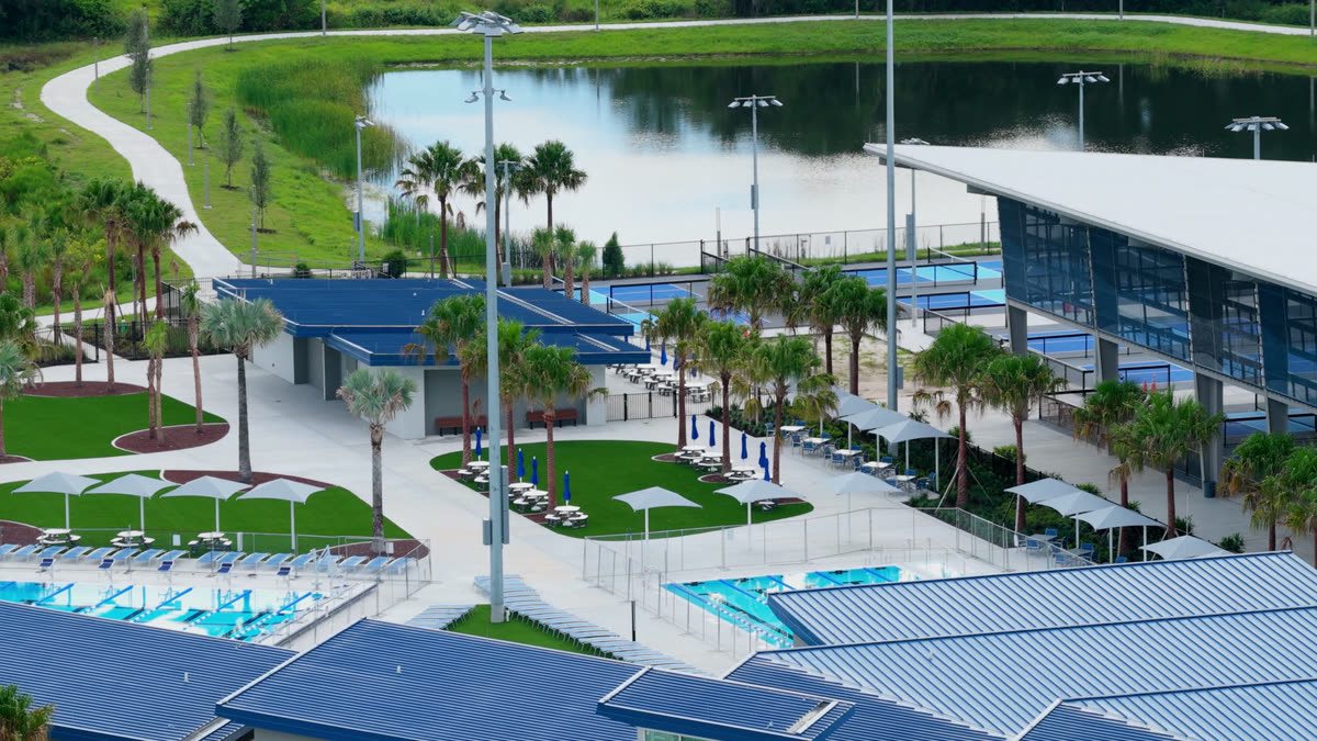 Aerial view of the campus grounds with a pond, a walking path and the covered court area